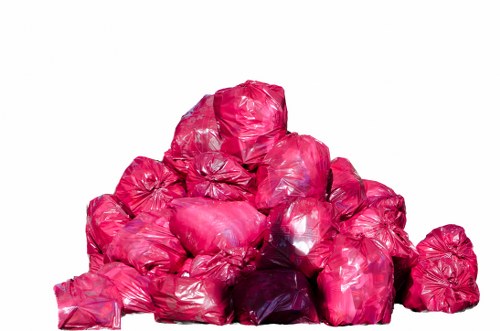 A pile of multiple bright pink rubbish bags made of plastic, tightly knotted at the top, stacked on a flat surface against a plain white background. The bags are of varying sizes, some slightly crumpled, with transparent areas revealing their contents, which appear to include general household waste. The arrangement suggests disposal or collection in progress, consistent with rubbish removal services such as those offered by Garden Clearance Balham. The environment is neutral, with no other objects or contextual elements visible, highlighting the focus on the waste bags. The lighting is even, with minimal shadows, emphasizing the vibrant colour and textured surface of the bags. This image is representative of waste disposal or rubbish clearance tasks one might encounter in an urban or suburban setting, particularly within the Balham area, and aligns with the company's service focus on rubbish removal.